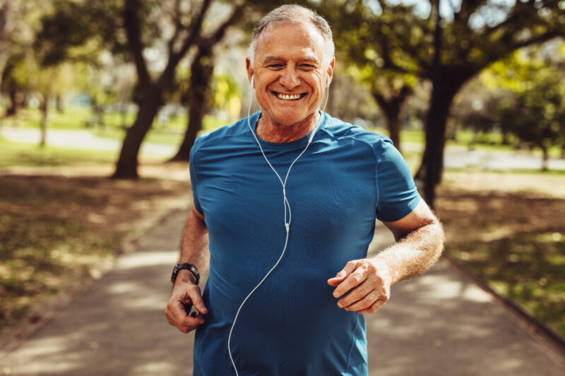 Older man jogging outdoors in a park, representing regular aerobic exercise for cardiovascular health and healthy aging.