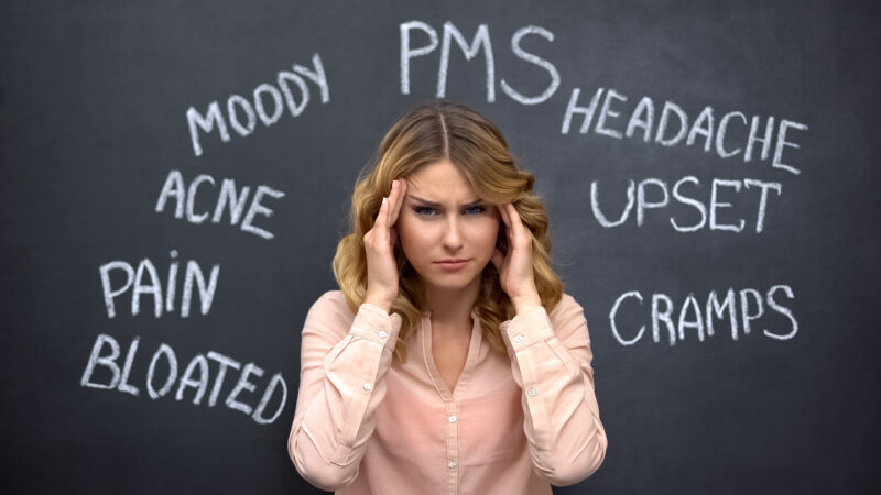 Woman experiencing headache and mood changes associated with PMS and perimenopause symptoms.