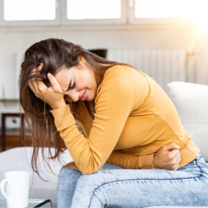 Woman experiencing abdominal pain, headache and fatigue, representing possible food sensitivity symptoms