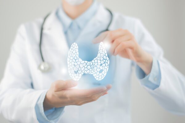 Doctor holding an illustration of the thyroid gland while discussing thyroid health and hypothyroidism.