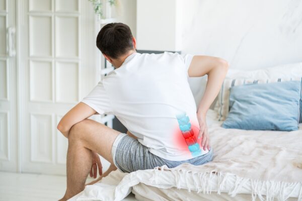 Man experiencing lower back pain with the lumbar spine highlighted