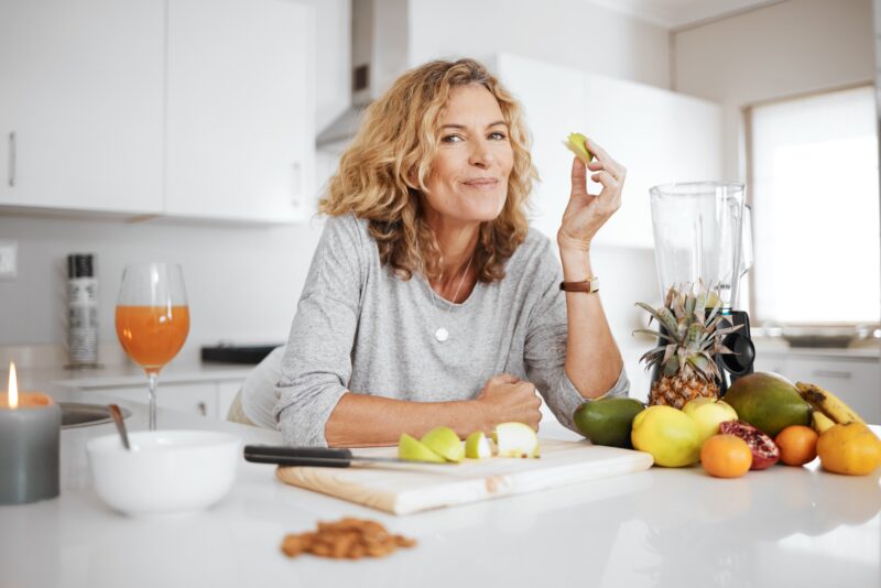 Woman in midlife preparing fresh fruit and healthy foods to support nutrition and wellness during perimenopause.