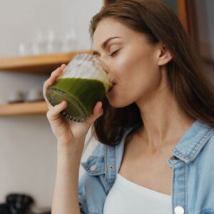 Woman drinking a green smoothie while enjoying a healthy whole-food meal