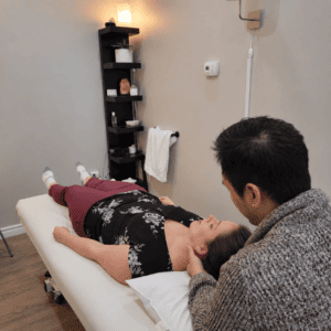 Osteopathic manual practitioner Sunny Ho providing gentle hands-on treatment to a patient’s neck in a treatment room at Hudson Integrative Healthcare.