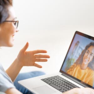 Woman speaking with a healthcare practitioner during a virtual psychotherapy appointment on her laptop.