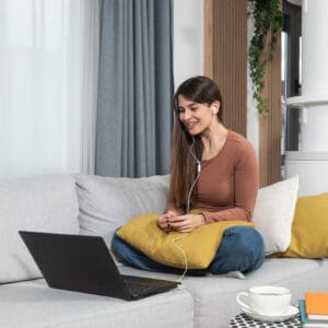 Woman participating in a virtual psychotherapy session from home using a laptop and headphones.