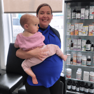 Dr. Melanie Hudson, pregnant and holding her baby, at Hudson Integrative Healthcare.
